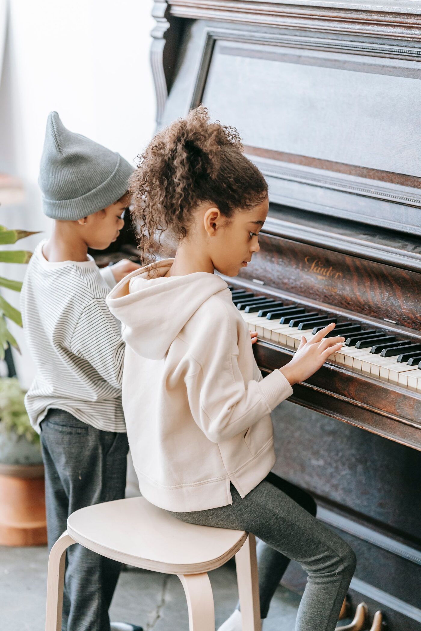 Two children playing piano together at home during an online lesson