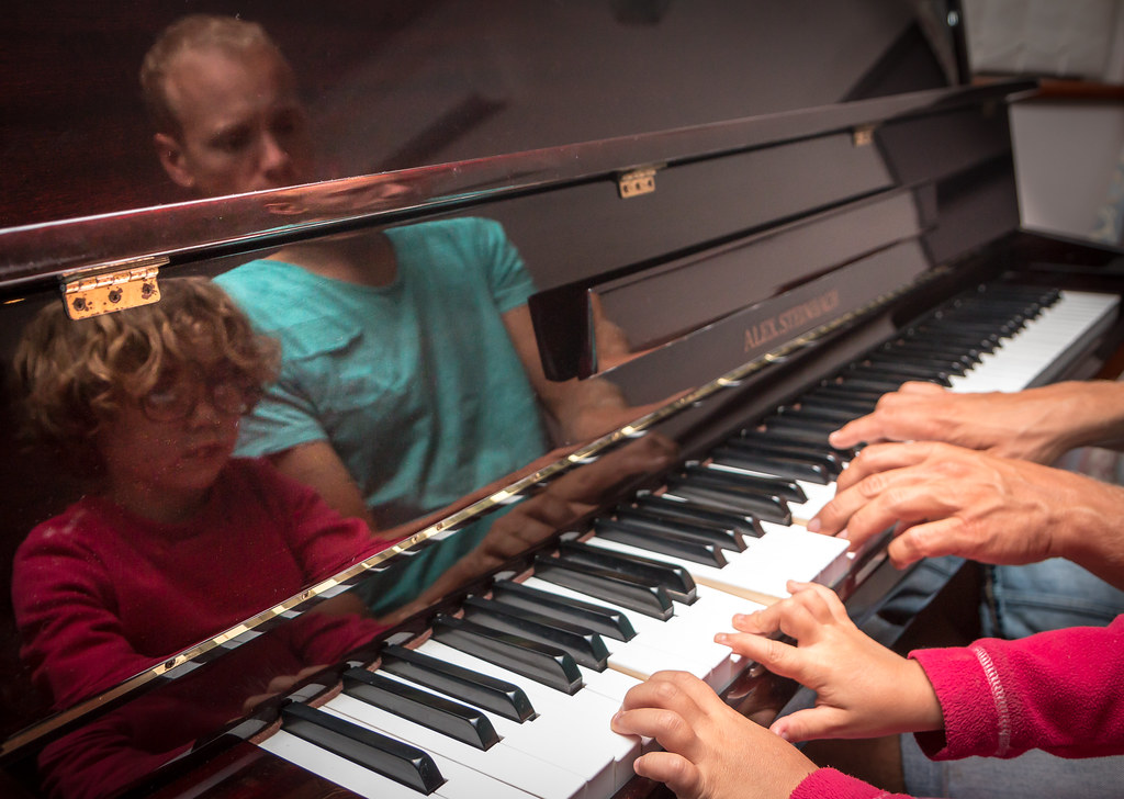 Parent and child practicing piano together during a lesson