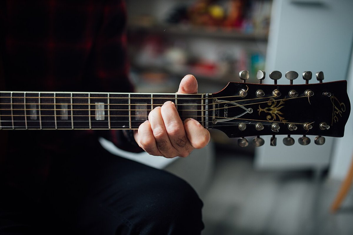 Close-up of a hand forming a chord on an acoustic guitar neck