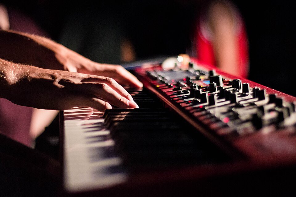 Close-up of hands playing a keyboard instrument on a dimly lit stage