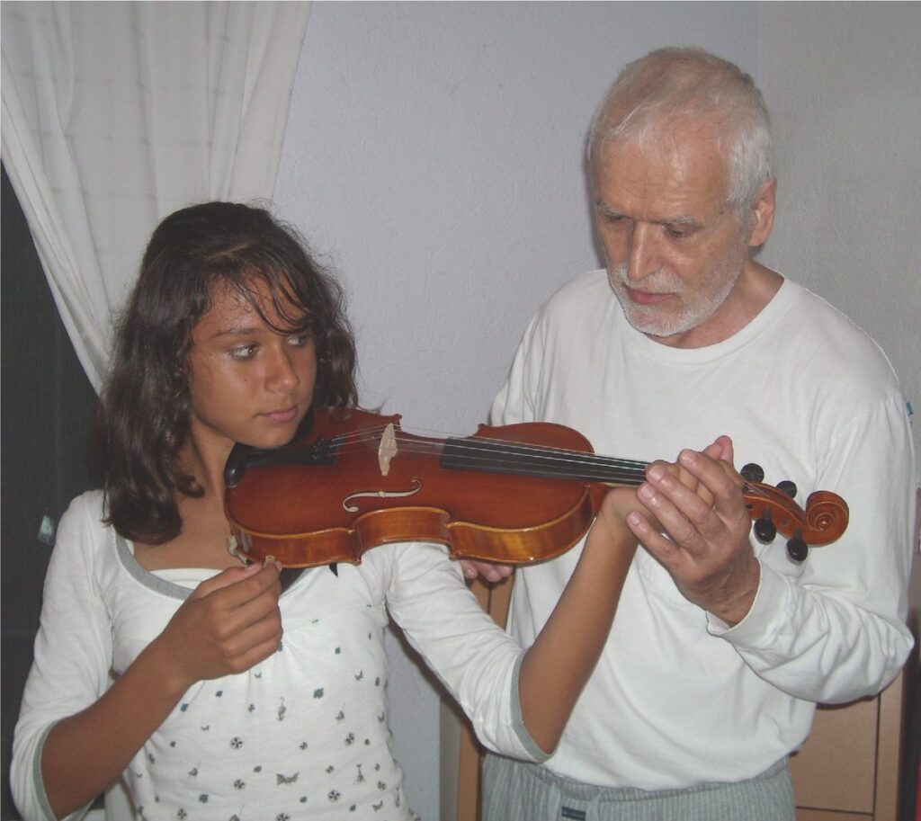 Music teacher guiding a student while she holds a violin during a lesson
