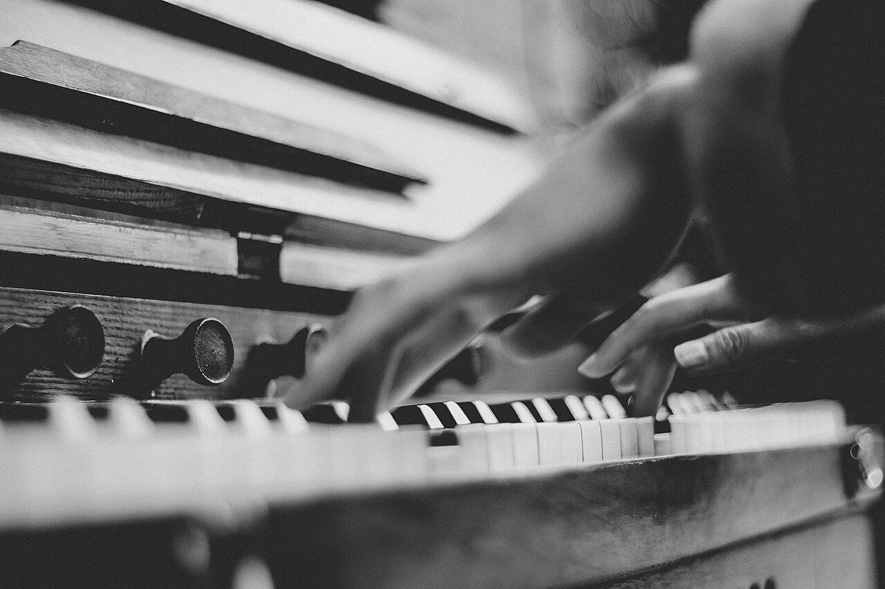 Blurred hands moving across an upright piano keyboard
