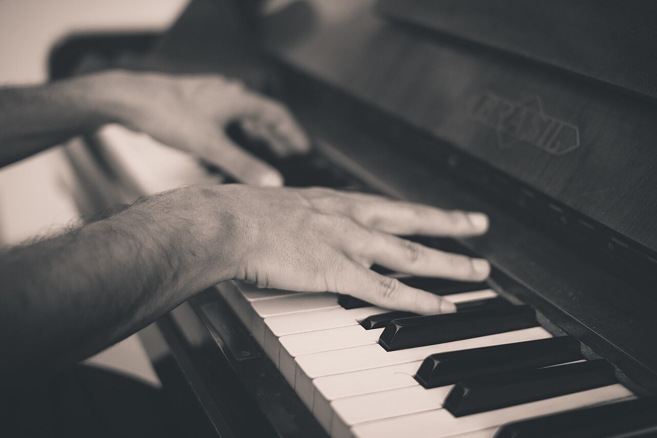 Pianist's hands resting on piano keys in black and white